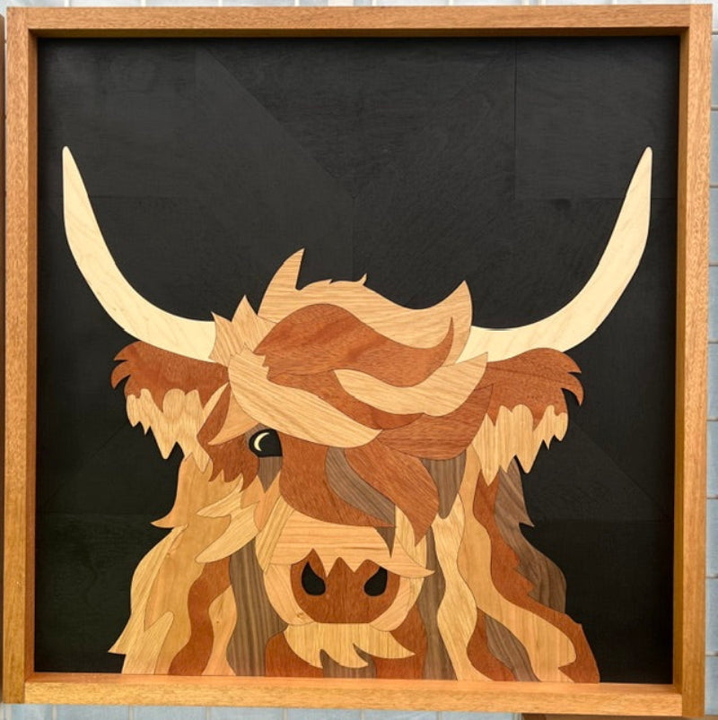 Wooden sculpture of a highland cow with large horns on a black background