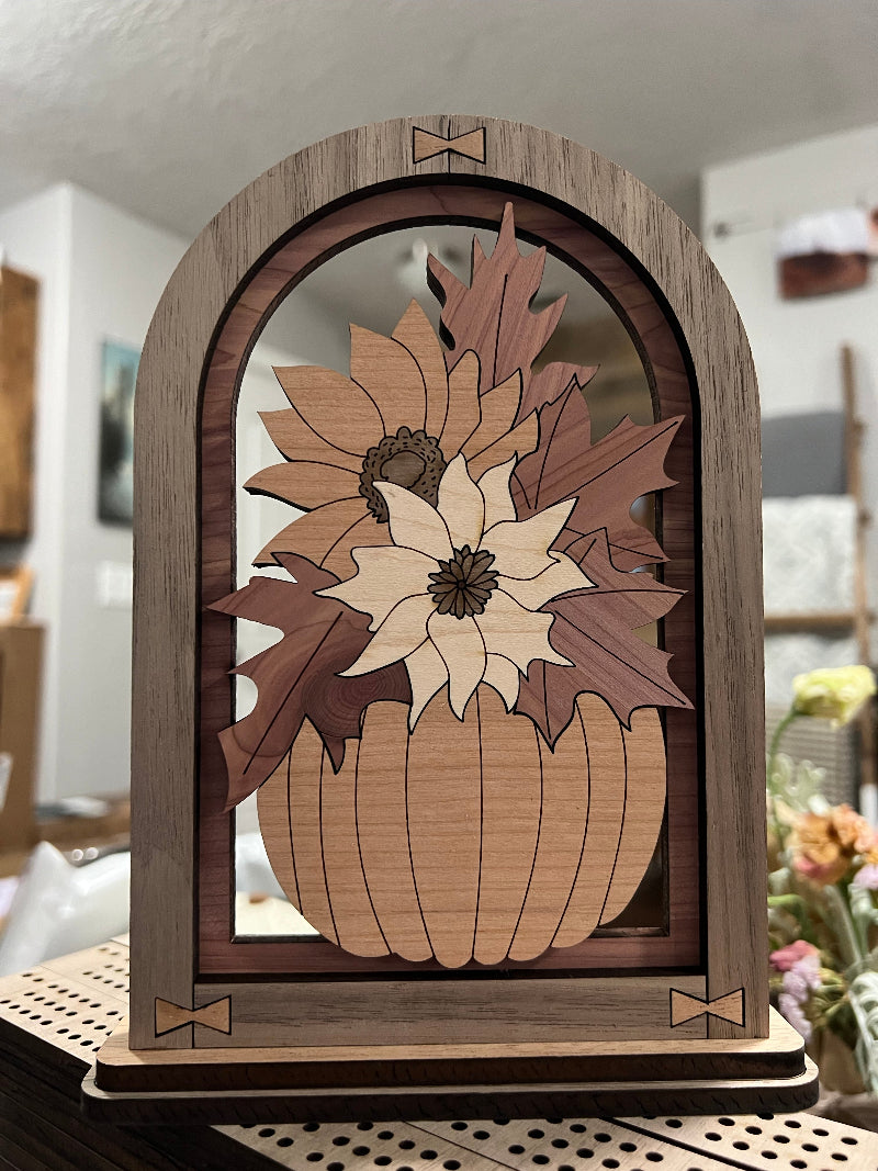 Wooden Pumpkin filled with foliage in multiple woods within an arched frame. Designed to sit on a shelf