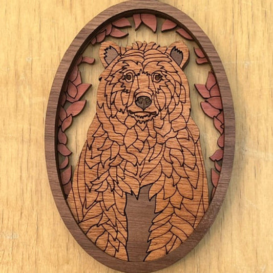 Wooden pendant with laser-cut design of a bear on a wooden surface