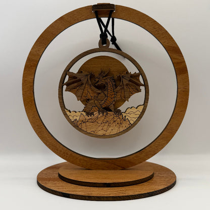 A laser-cut wooden dragon ornament displayed on a circular wooden stand against a plain light background.