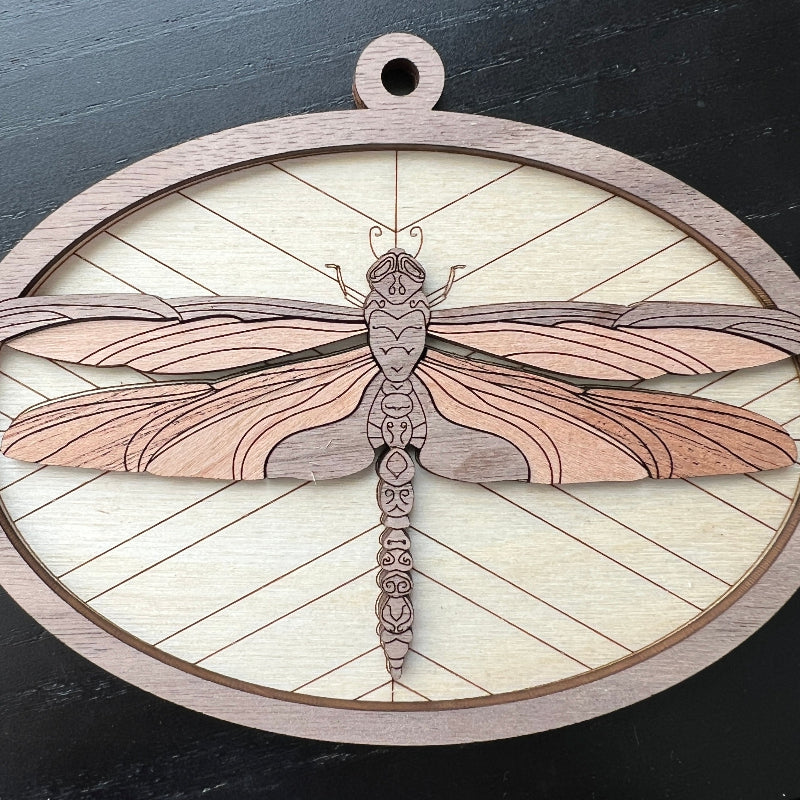 A wooden ornament with an intricate dragonfly design on a geometric background