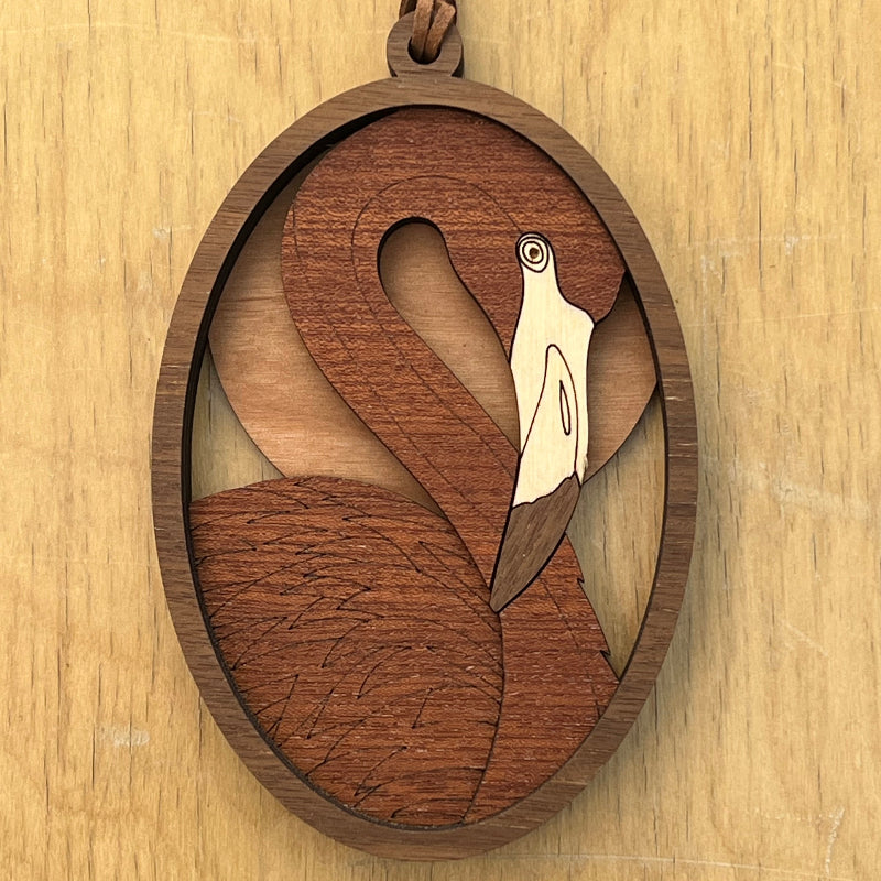 A wooden ornament with a flamingo design on a light wood background
