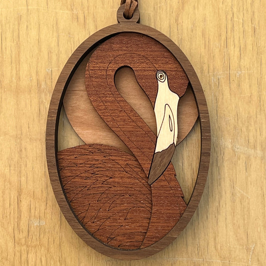 A wooden ornament with a flamingo design on a light wood background
