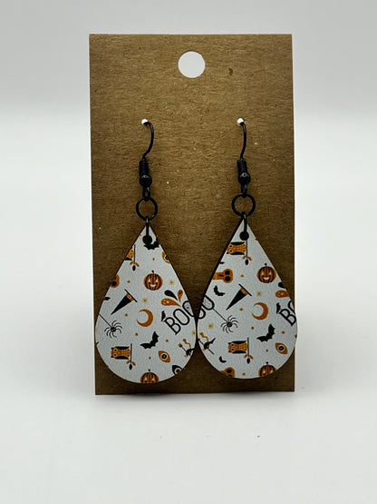 White teardrop earrings with UV printed Halloween designs including hats, bats, owls, and jack-o'-lanterns