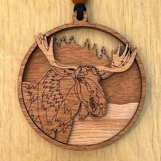 Wooden pendant with engraved Moose design on a wooden surface