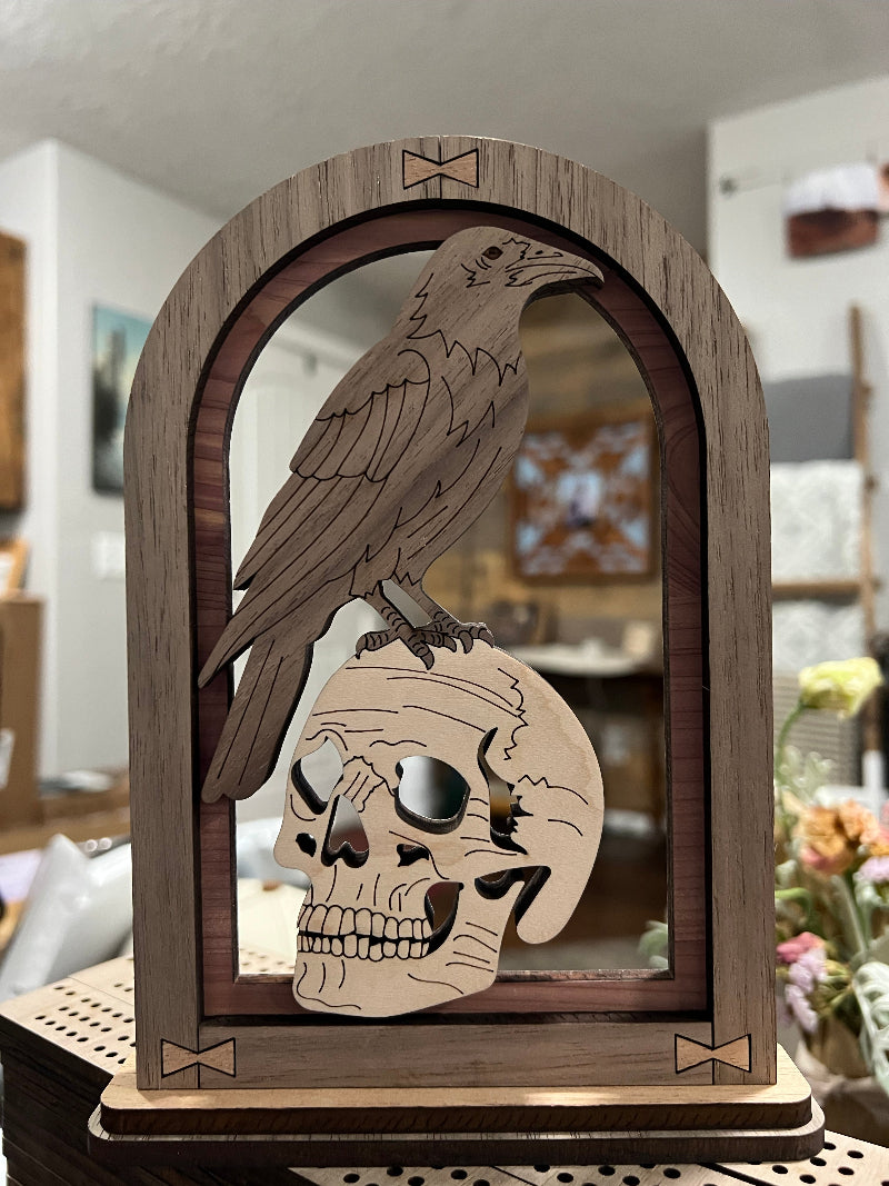 Wooden shelf sitter art with a skull and raven design 