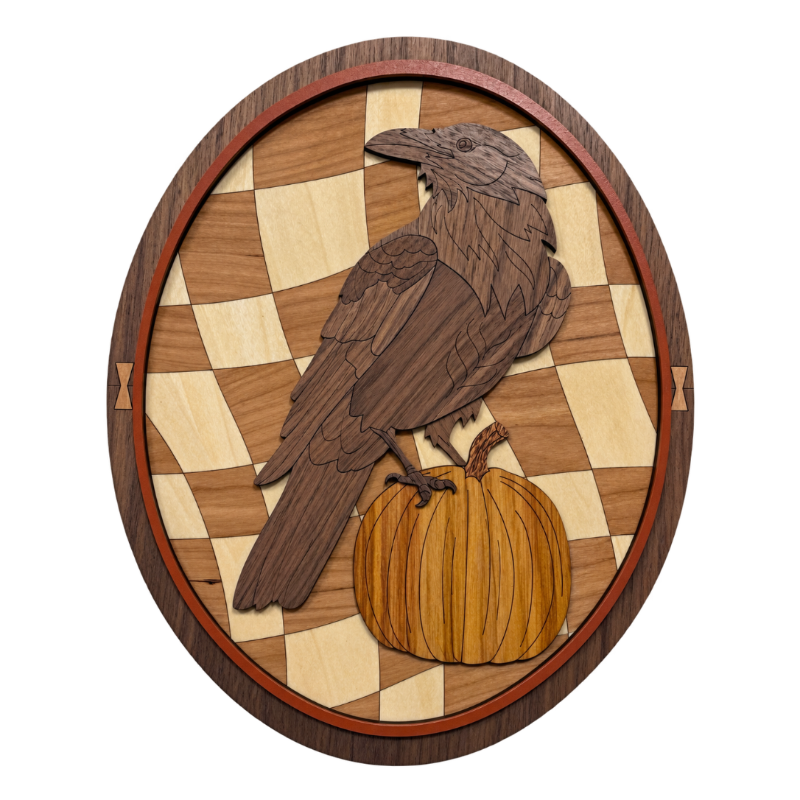 Oval wooden wall art featuring a laser cut raven perched on a pumpkin over a checkerboard background, shown on a plain white background.