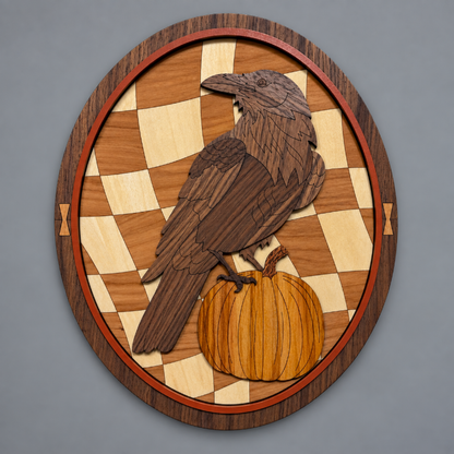 An oval wooden wall plaque featuring a laser cut raven perched on a pumpkin, set against a checkered wood background with a dark wood border.