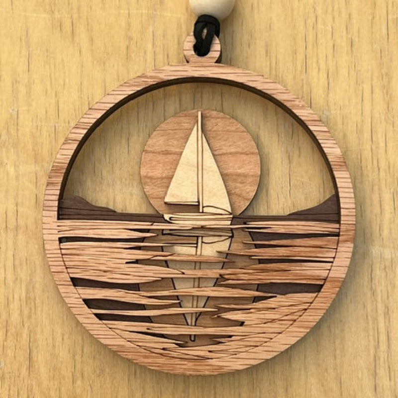 Wooden decorative item with a circular sailboat at sunset design on a wooden surface