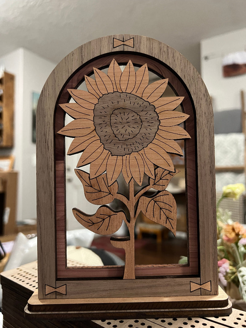 Wooden Sunflower in multiple woods within an arched frame. Designed to sit on a shelf