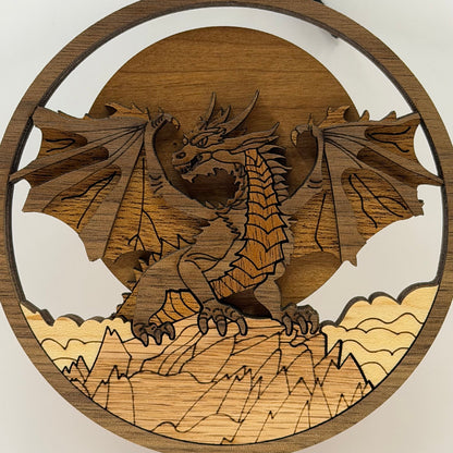 A circular wooden dragon wall hanging featuring a laser-cut dragon perched on mountains, with a sun and moon design in the background.