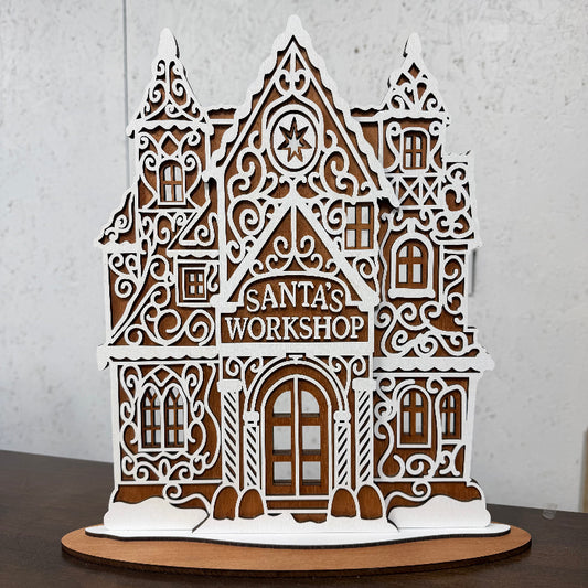 Wooden gingerbread Santa's Workshop in mahogany with white frosting overlays and a Santa's Workshop sign above the door, 14 inches tall