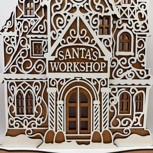 Close-up of the Santa's Workshop sign and white MDF frosting details on the mahogany gingerbread workshop
