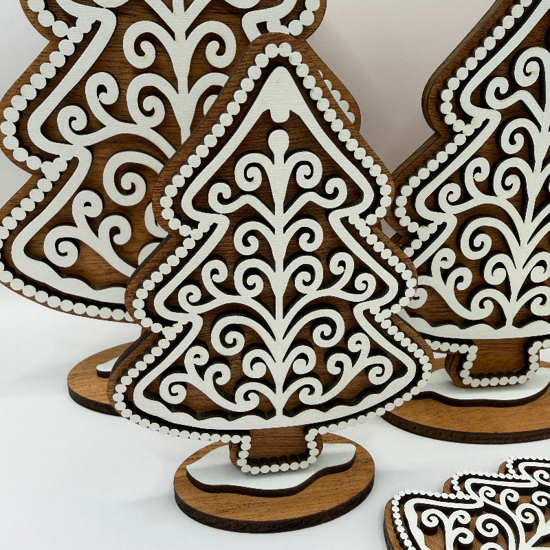 close up of a wooden gingerbread style tree with a dark wood background and a white frosting design