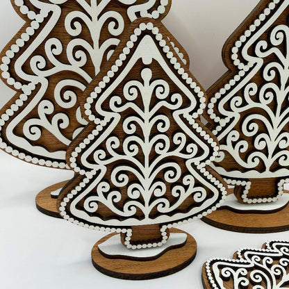 close up of a wooden gingerbread style tree with a dark wood background and a white frosting design
