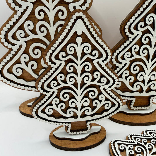 close up of a wooden gingerbread style tree with a dark wood background and a white frosting design