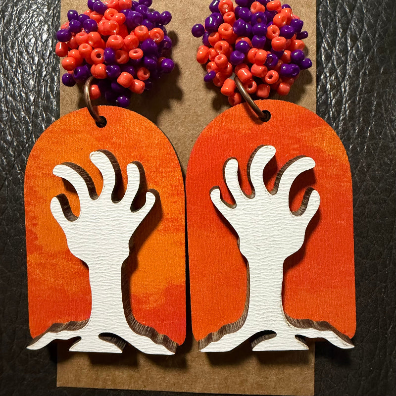 Tombstone with zombie hands earrings shown from another angle