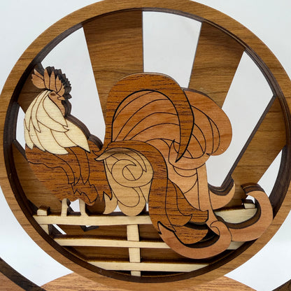 A circular wooden rooster figurine with layered laser-cut wood pieces in varying shades of brown and natural wood tones, set against a white background.